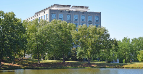exterior of hotel beside trees and a lake
