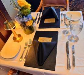 a table set with menu, napkin, accent lighting, and a flower
