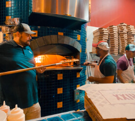 putting a pizza in the wood fired oven