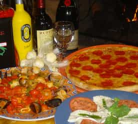 three different Italian dishes and wine on a table