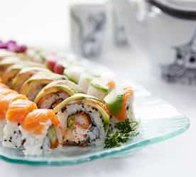 sushi on a plate with tea pot in background