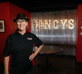 owner in front of restaurant name lit up behind her