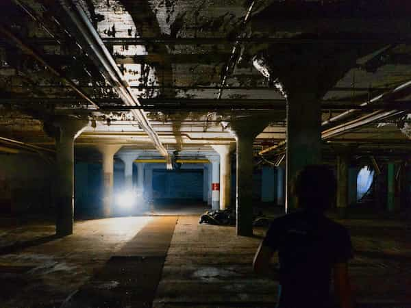 a guy walking through an eerie parking deck