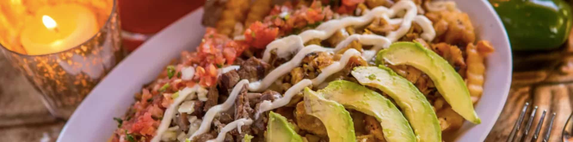 close-up of a Mexican dish with avocados and a candle in the background