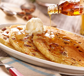 pouring syrup over pancakes