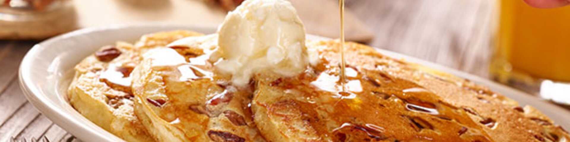 pouring syrup over pancakes breakfast