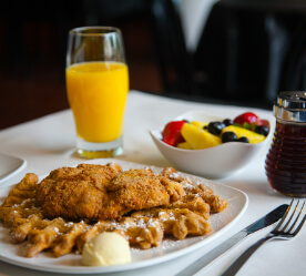 fried chicken on a waffle with fruit and OJ