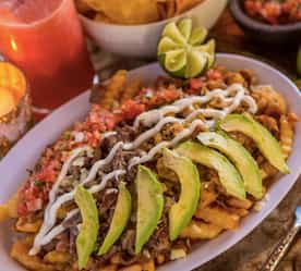 Mexican dish with avocado and other garnishes and candle in background