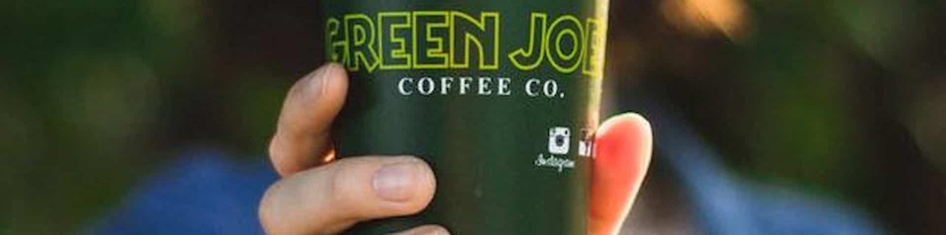 holding a coffee cup with Green Joe's logo