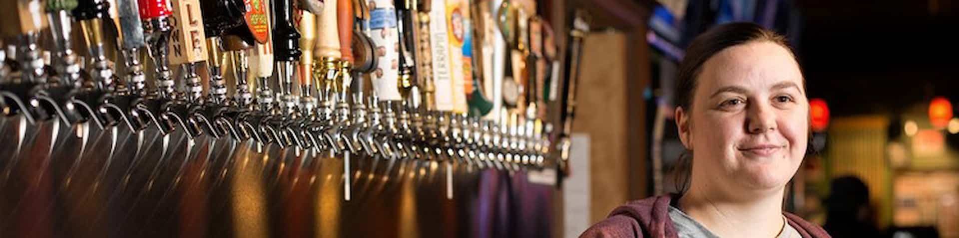 bar tender standing in front of beer taps