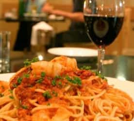 pasta with a glass of wine and other seating in background