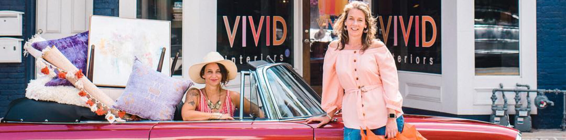 two ladies with a red convertible full of home goods