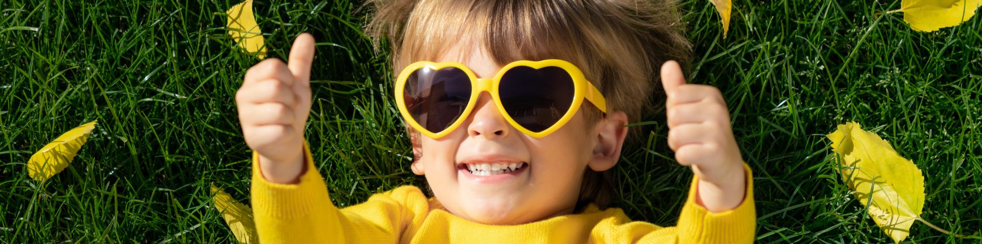 a little kid laying in the grass looking happy