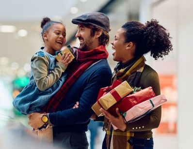 a dad holding a little girl and the mom and dad both smiling  while shopping